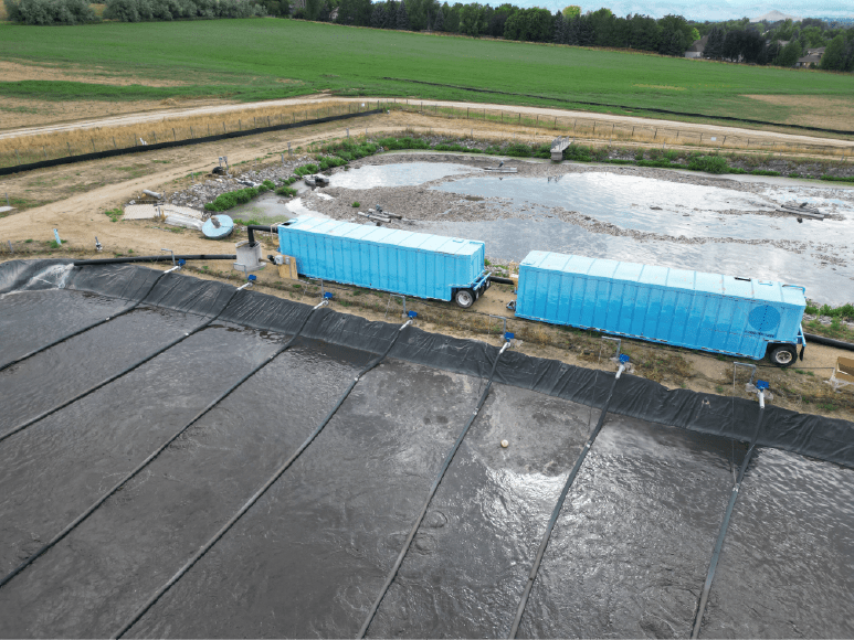 A large water treatment plant with a blue truck and frac tanks that manage debris for aeration basin treatment.