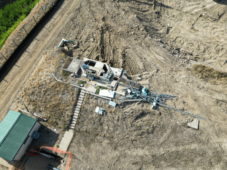 Aerial perspective of a construction site with a crane, where frac tanks are used to settle debris amid the demolishing of the old Headworks building.