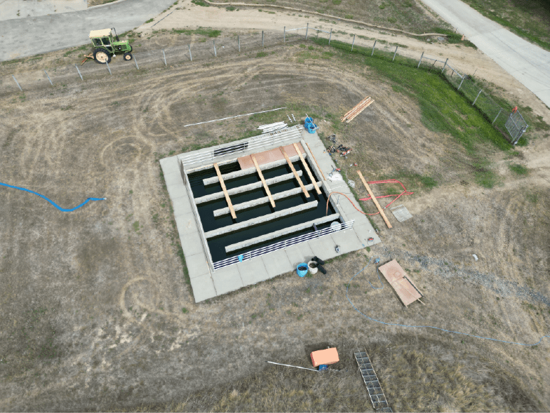 Aerial image of a construction site showcasing a partially covered chlorine contact chamber and the start of a UV building project.