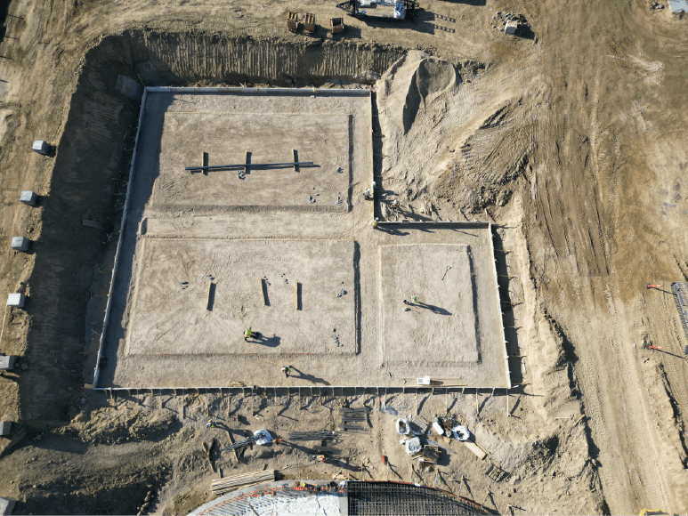 Aerial view of a leveled construction site with a future dewatering facility in the background, showcasing excavation work.