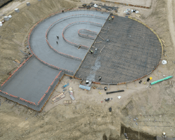 Aerial perspective of a concrete pump being set up, with rebar in place and half of the slab completed in a major pour.